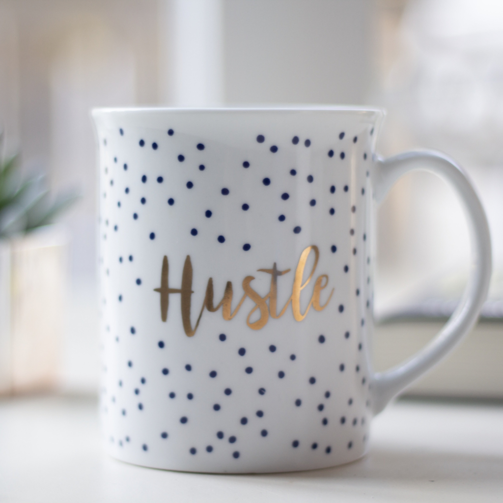 Coffee mug that says "Hustle" on it for wow we paid off debt of $67,630 in 16 months