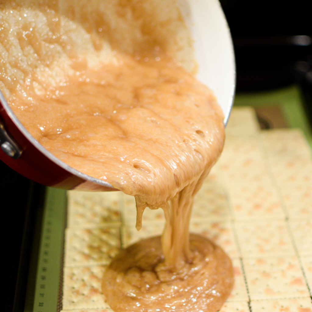 Toffee being poured over crackers for easy Christmas crack recipe