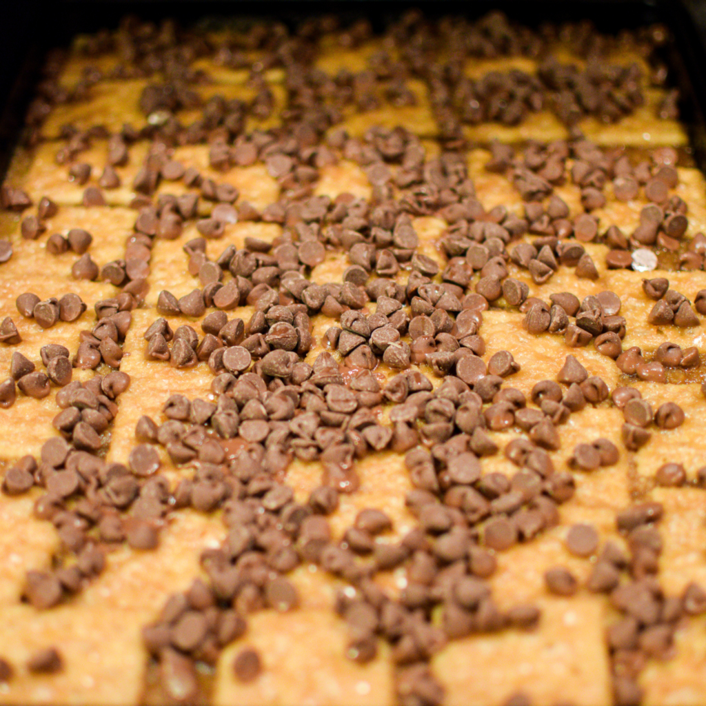 Chocolate chips sprinkled on toffee crackers for easy christmas crack recipe