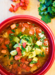 Red bowl filled with healthy lime chicken & avocado soup