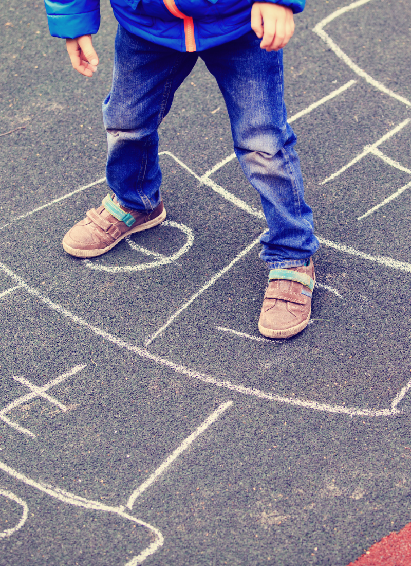 Child playing hopscotch for backyard play ideas for kids