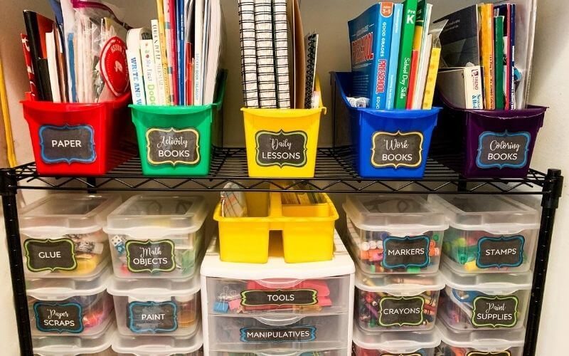 Storage bins with colorful homeschool supplies. 