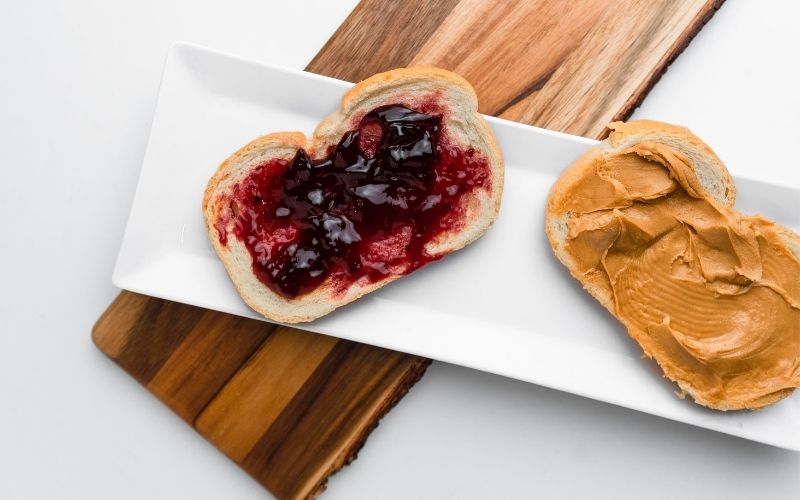 Bread with peanut butter and jelly on it for Cheap Foods To Buy When You're Broke & Hungry