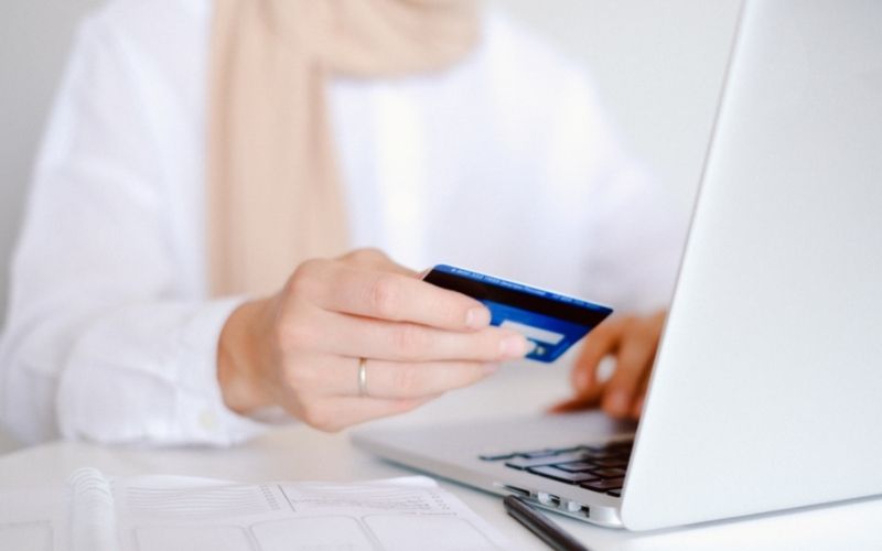 woman holding credit card in hand at computer