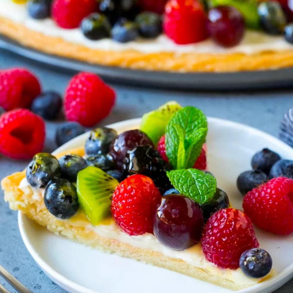 fruit pizza with blueberries, kiwi, strawberries, cherries on a white plate
