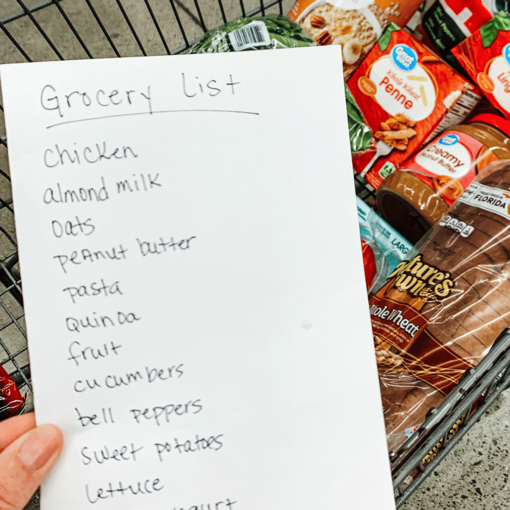 Grocery list with healthy options over top of a shopping cart with grocery items