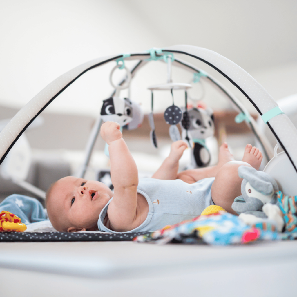 Baby on its back playing with a baby gym