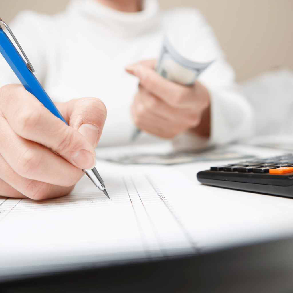 Person holding money and writing out a budget for baby budget worksheet