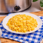 White plate on a blue checkered cloth containing slow cooker corn casserole